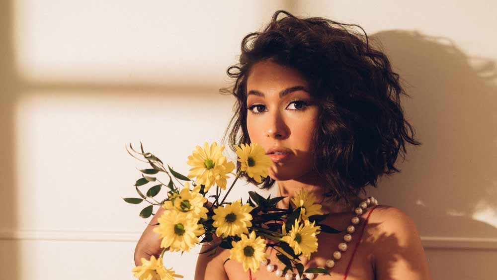 Nella in a red sundress holding yellow flowers
