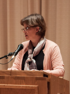 Rebecca speaks at a microphone