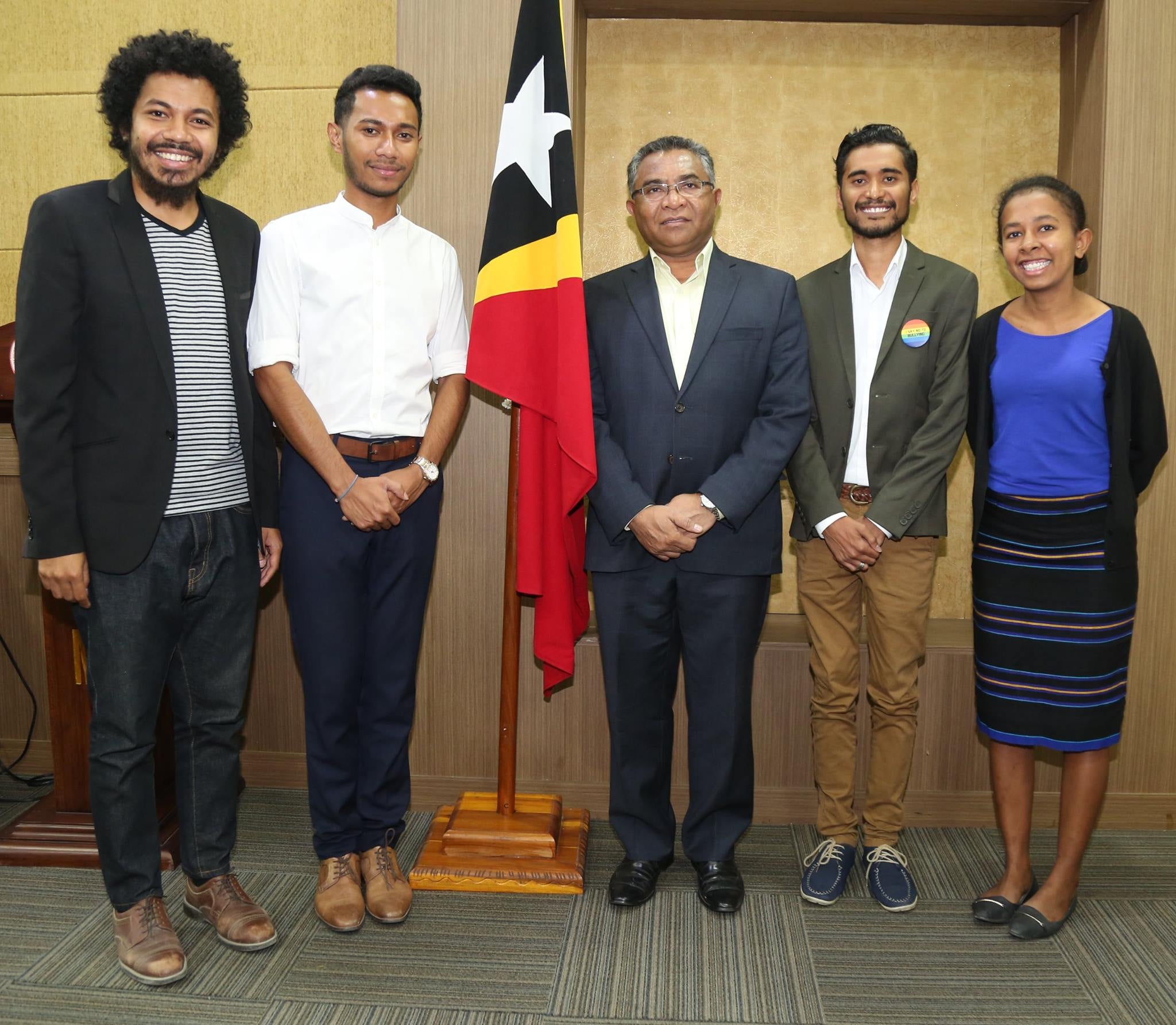A group of five people stand with a Timor-Leste flag