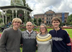 The Chamberlain family wearing Norwegian sweaters, in front of two ornate buildings