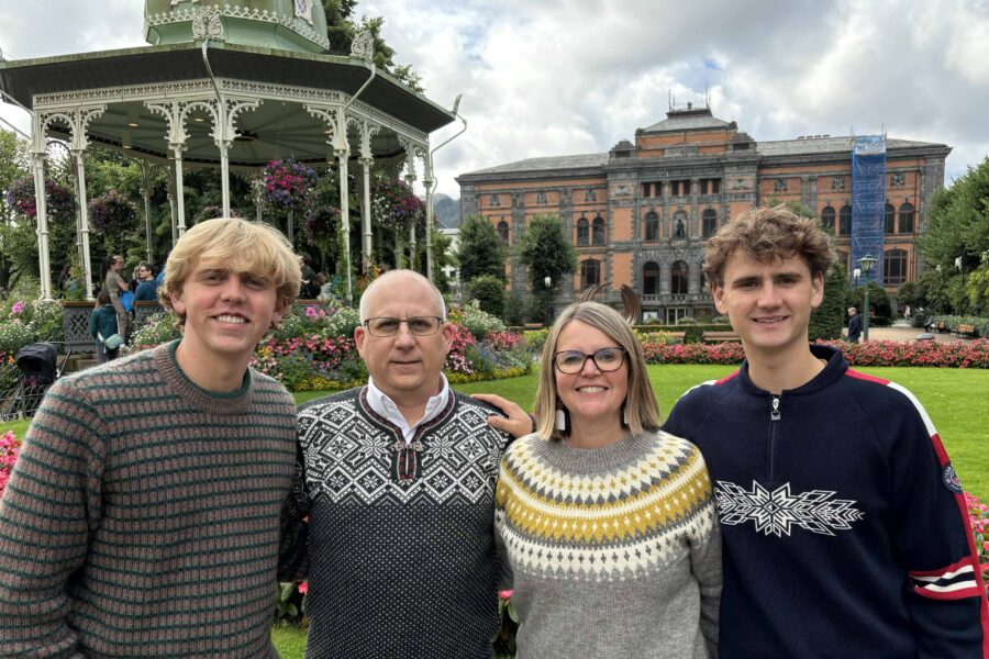 The Chamberlain family wearing Norwegian sweaters, in front of two ornate buildings