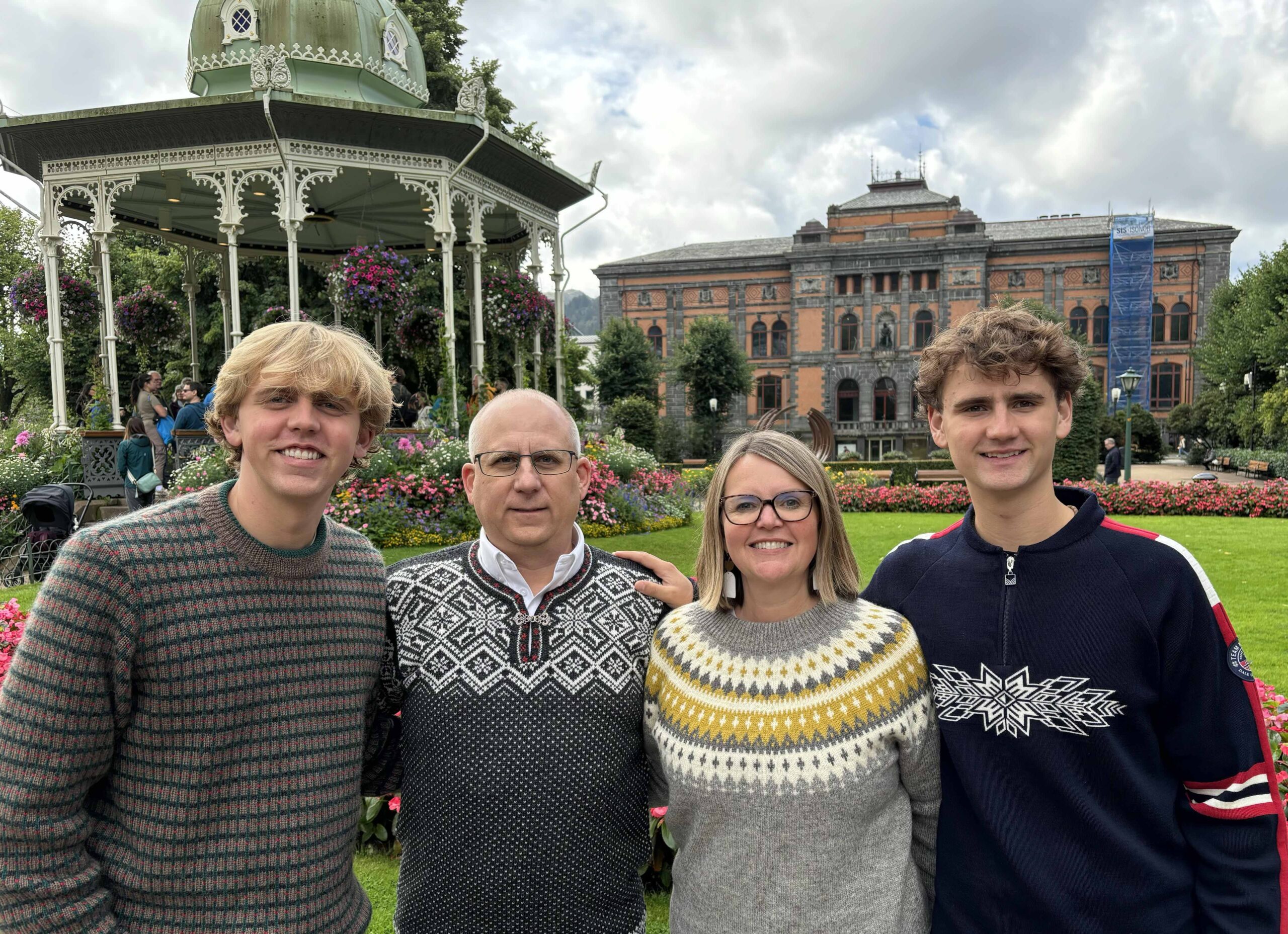 The Chamberlain family wearing Norwegian sweaters, in front of two ornate buildings