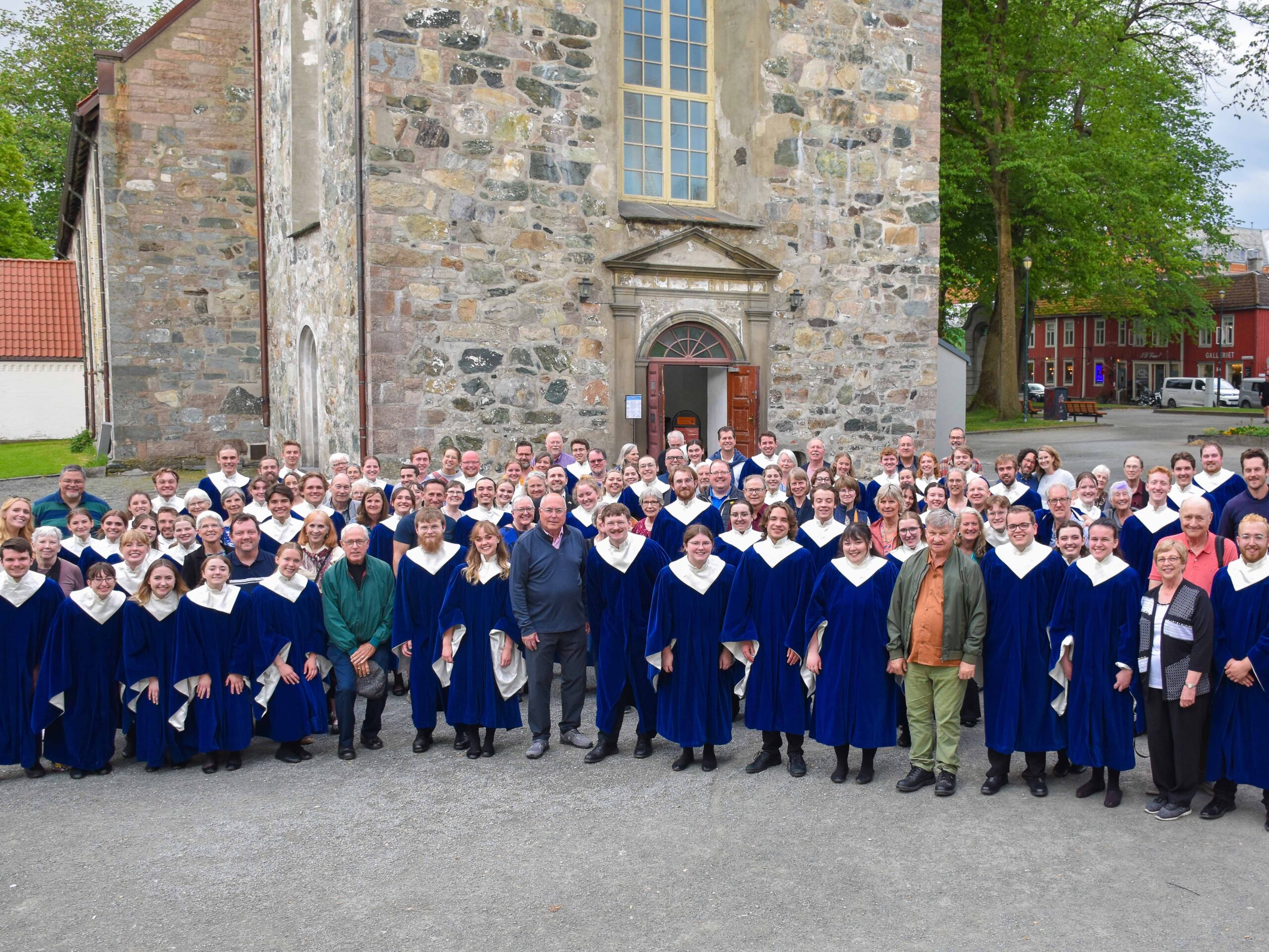 Nordic Choir in robes stands in front of an old church