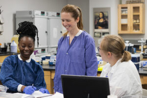 Two students and a professor work together in a microbiology lab.