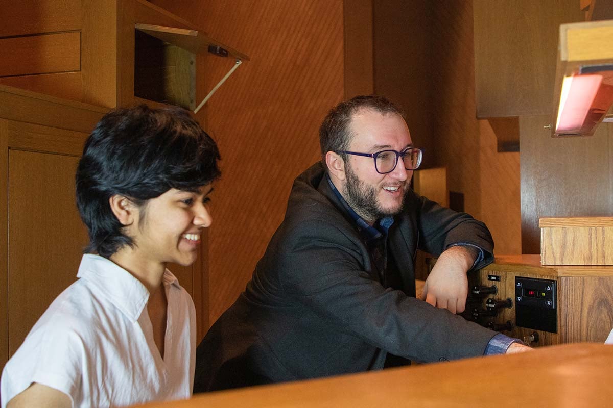 A student sitting next to a professor at an organ