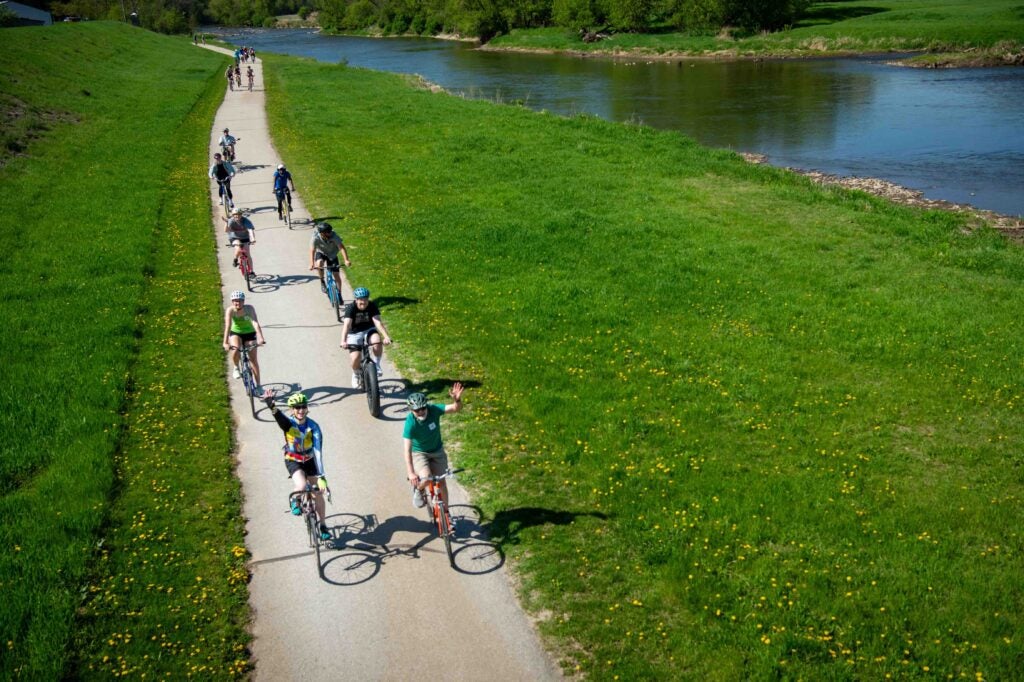 Cyclists ride on a trail along a river