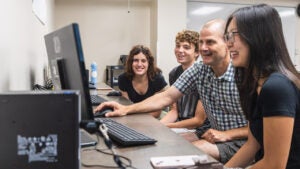 college students and their professor look at computer screen