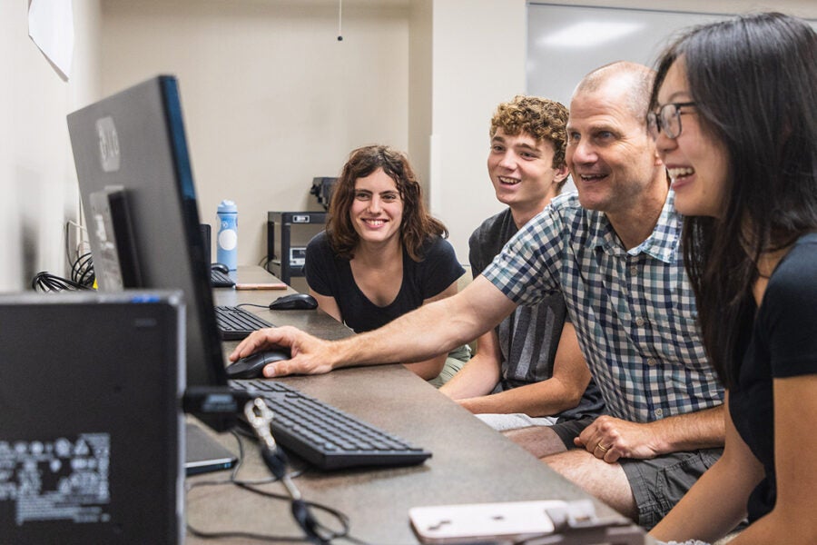 college students and their professor look at computer screen