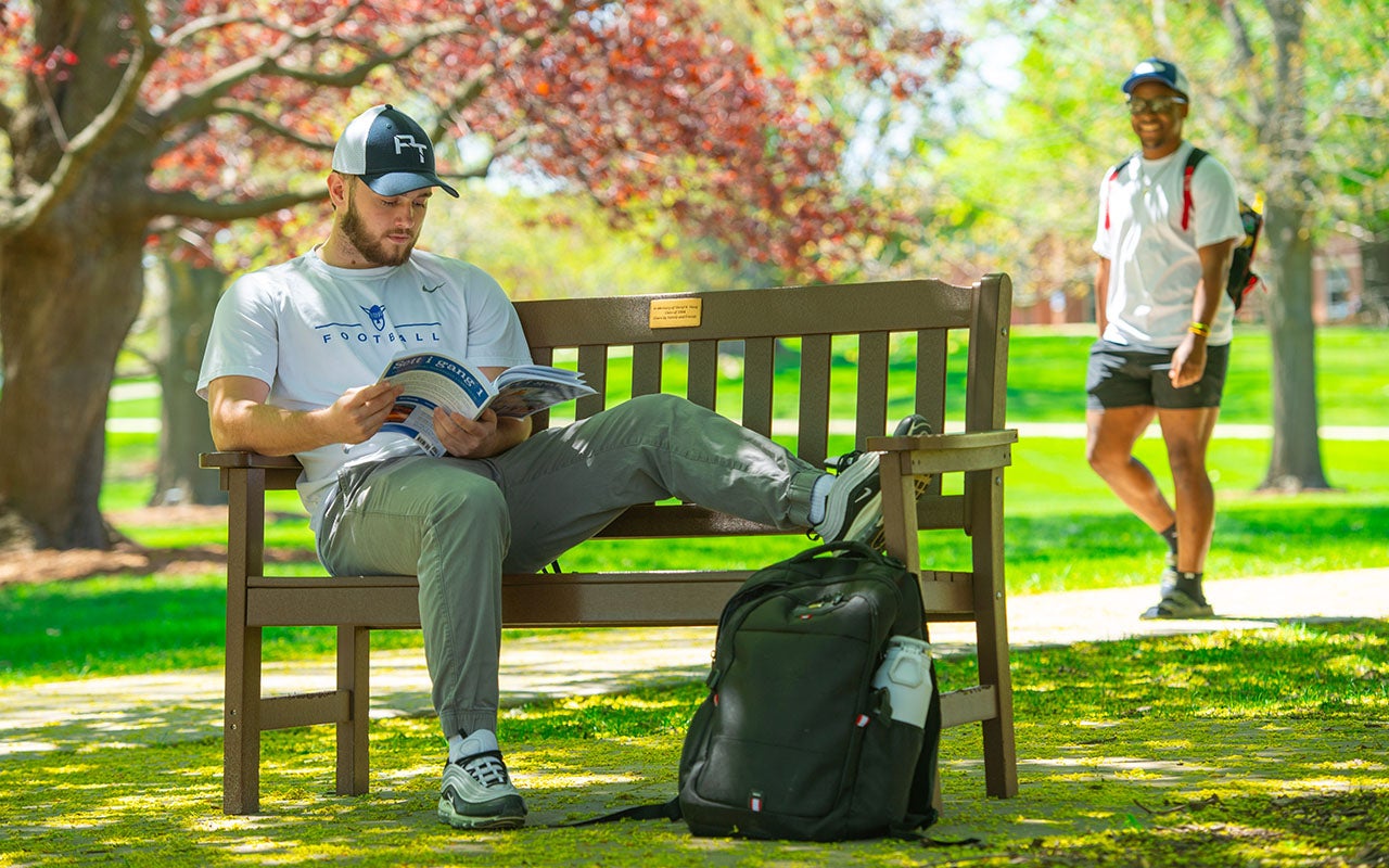 Luther student reading on a bench outdoors