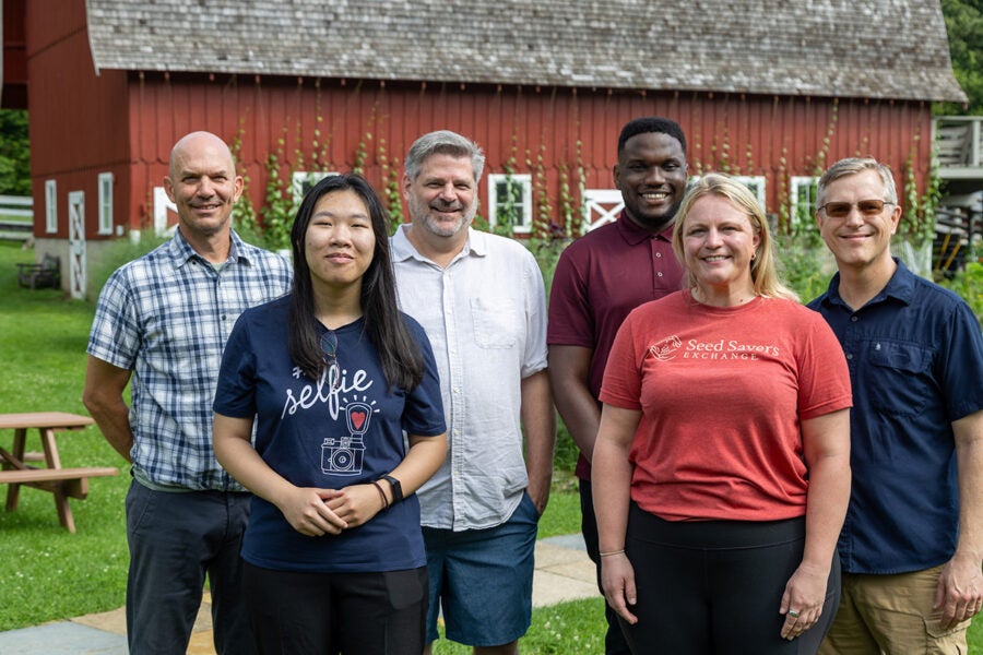 Group of people gather for a photo in front of the red barn at Seed Savers Exchange farm.
