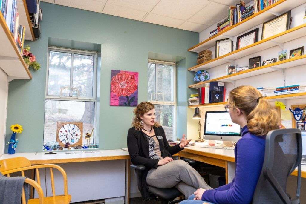 Student sits with an advisor in a colorfully decorated office.