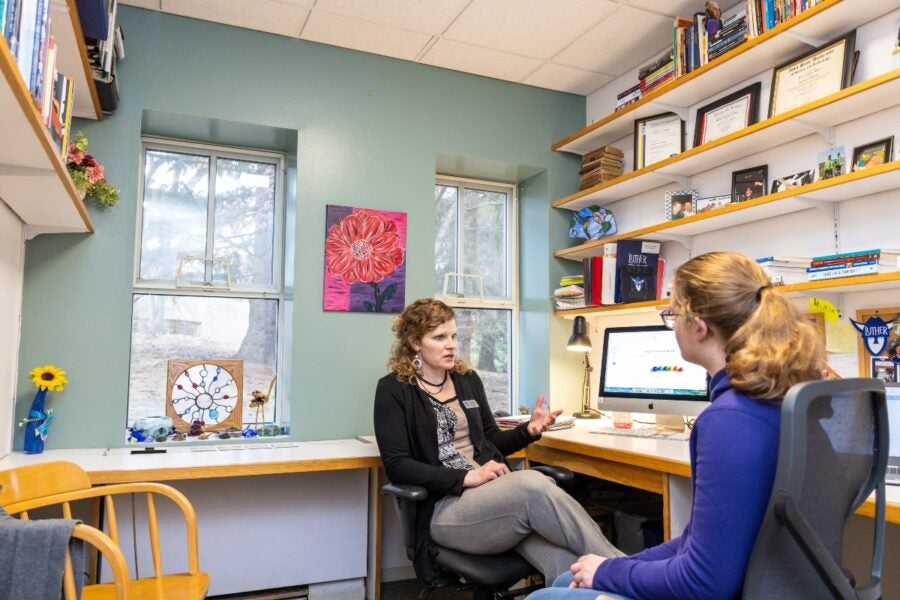 Student sits with an advisor in a colorfully decorated office.