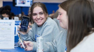student-athlete holds up photo and smiles at camera