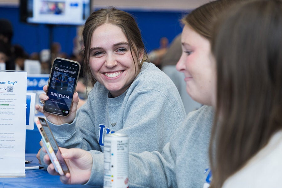 student-athlete holds up photo and smiles at camera