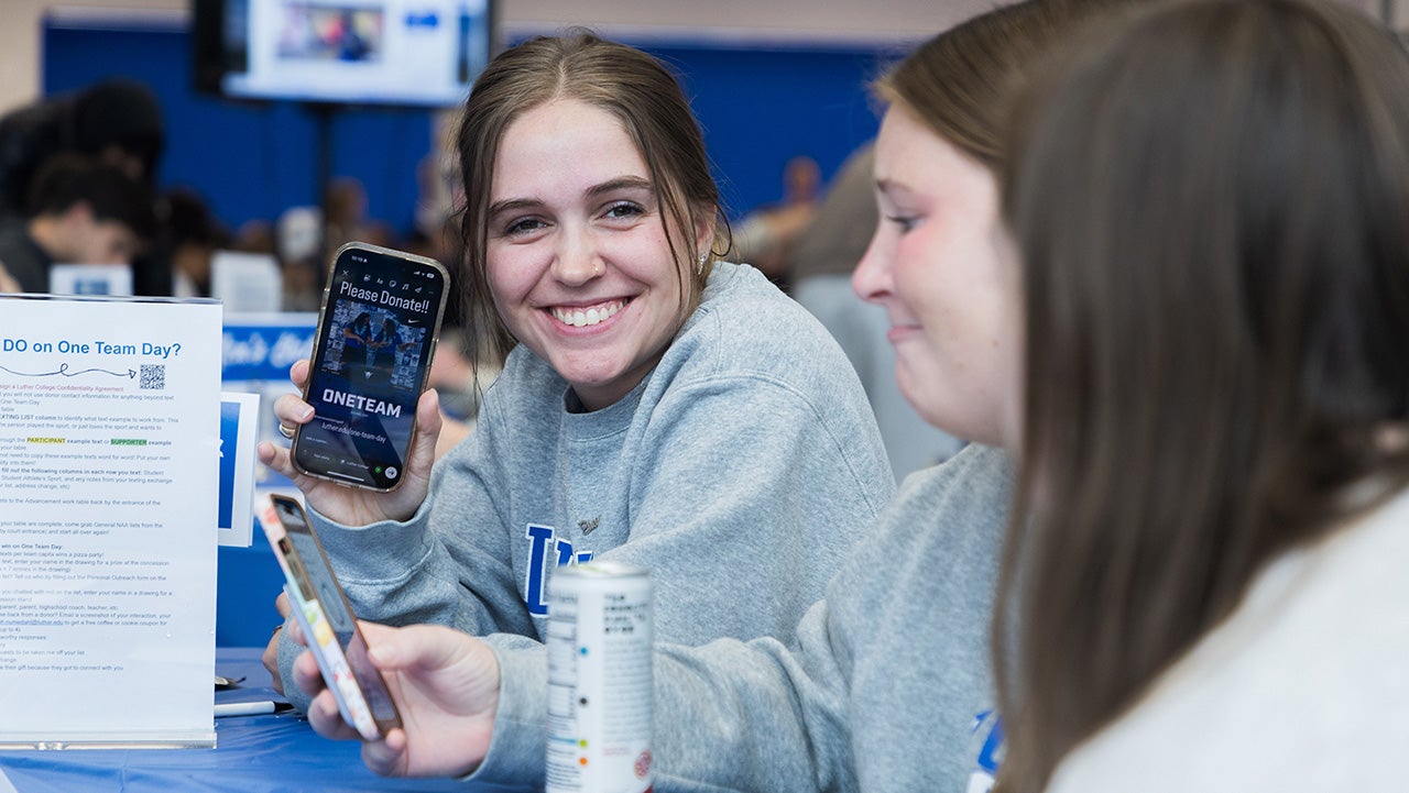student-athlete holds up photo and smiles at camera