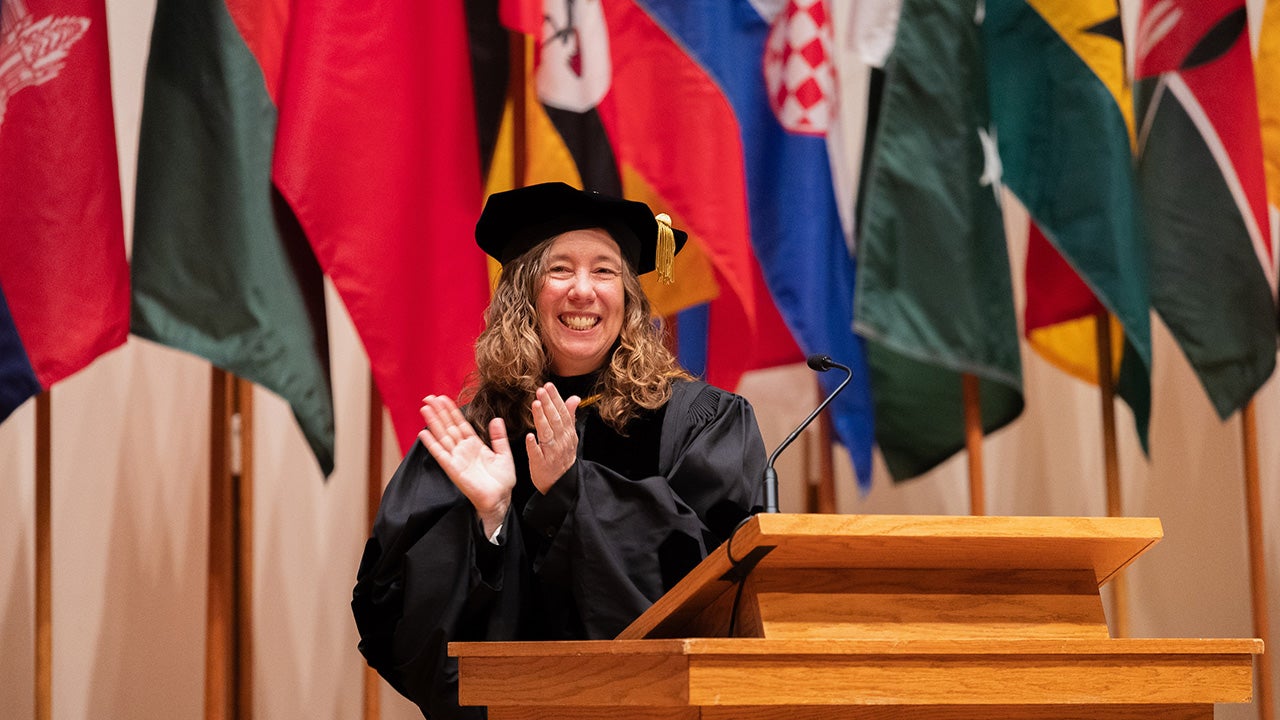 Luther College Provost Pam Bacon applauds at a ceremony.
