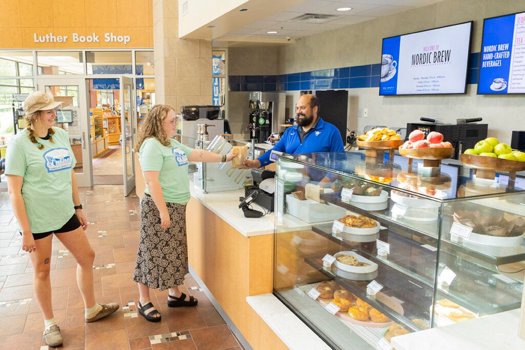 two students stand at the Nordic Brew counter, receiving a package from the server