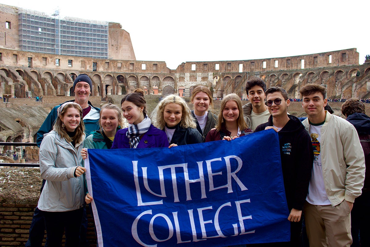 Students with Professor Holland in Malta holding a Luther College flag