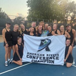 women's tennis team with conference champion banner