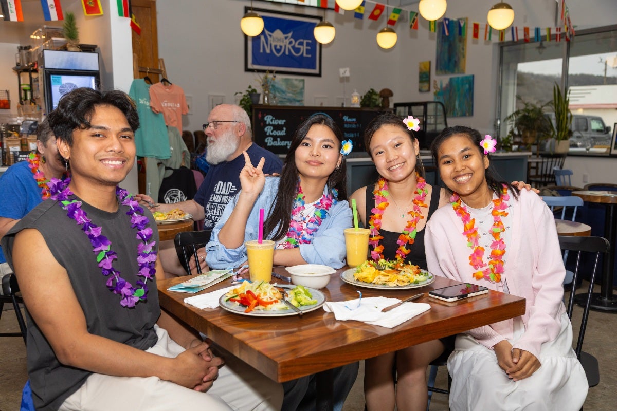 Students wearing leis eat a colorful meal at the Landing Market.