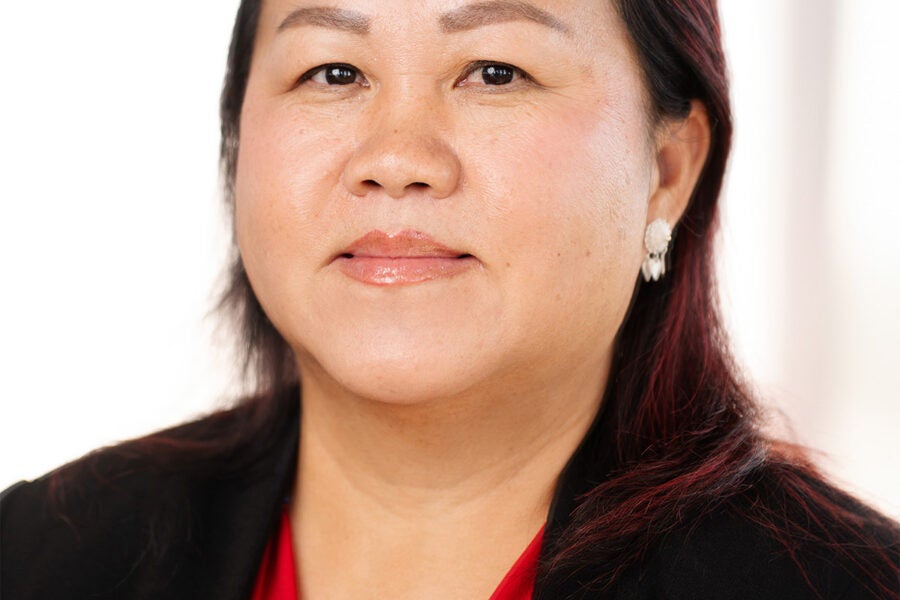 professional headshot of a woman wearing a red and blue patterned blouse and a black jacket.