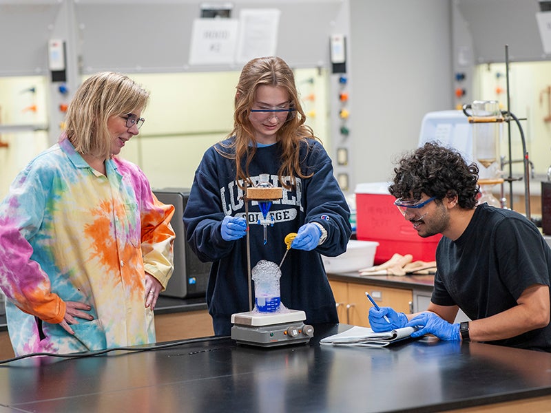 A professor and two students doing a chemistry experiment.