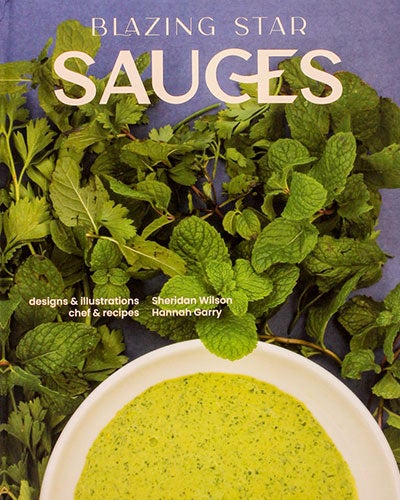 A cookbook cover that features a bundle of herbs and a bowl of speckled lime green soup or sauce