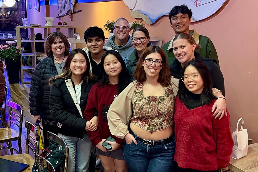A group of 10 posing happily together in a restaurant