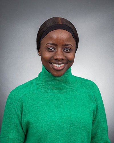 A smiling woman in a green sweater against a gray background