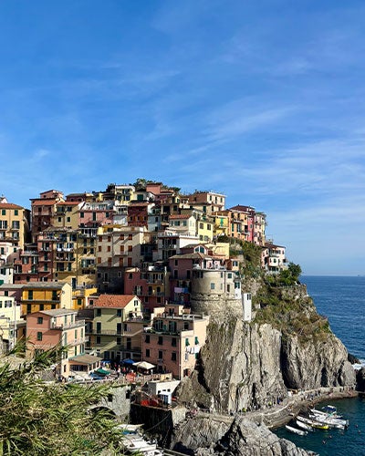 A dense village built at multiple levels upon a rocky outcropping against a blue sky