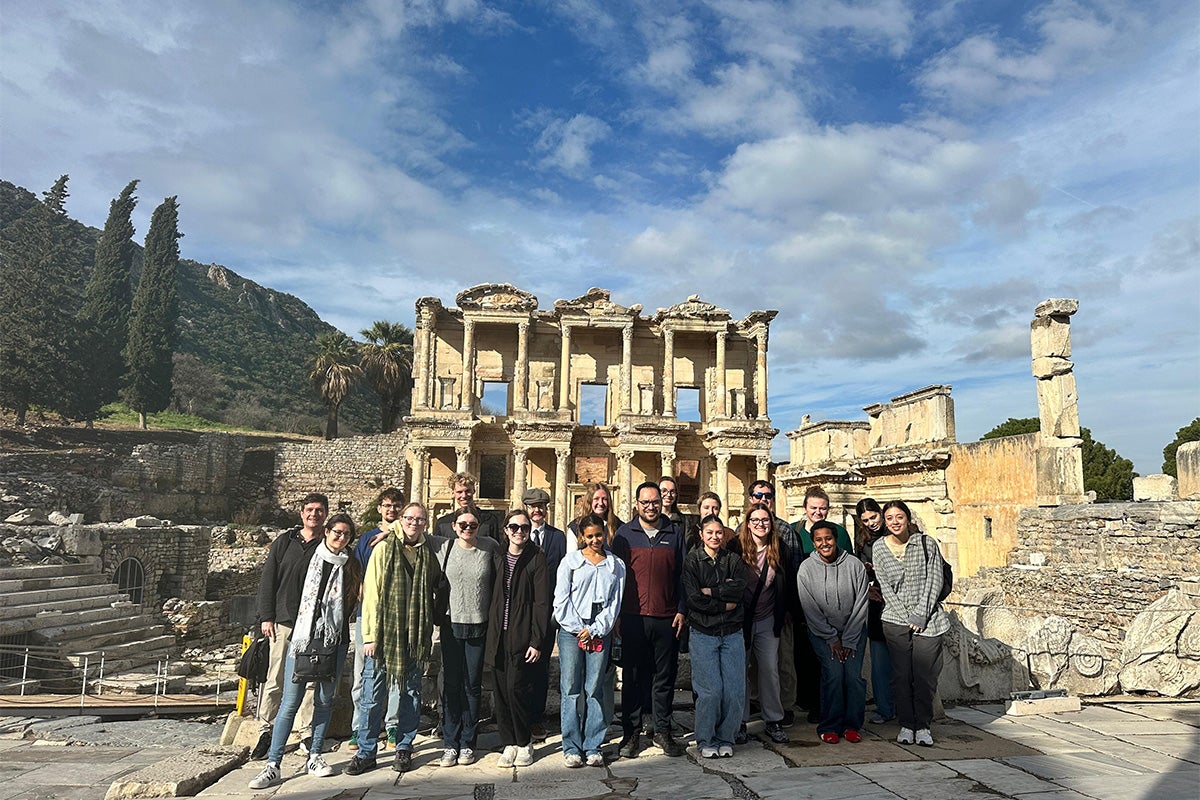 two college professors and 18 college students stand for a photo in front of the ruins of the ancient city of Ephesus in Turkey.