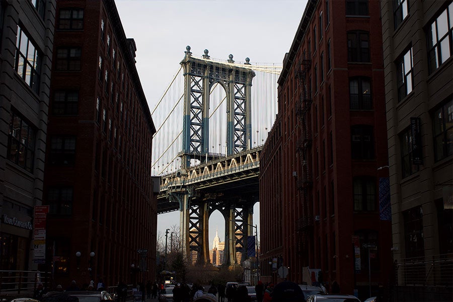 Tall dark buildings on the left and right frame a large bridge in the center