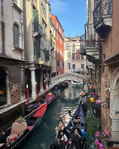 Venetian canals with multistory buildings right against the water and multiple passenger boats in the water