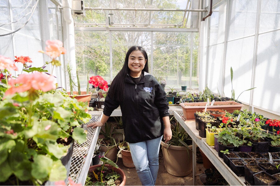 Luther College student stands for a photo inside the greenhouse.