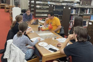 college professor and students play board game inside a library