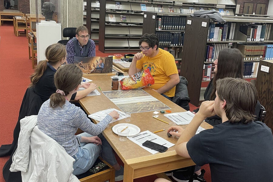 college professor and students play board game inside a library
