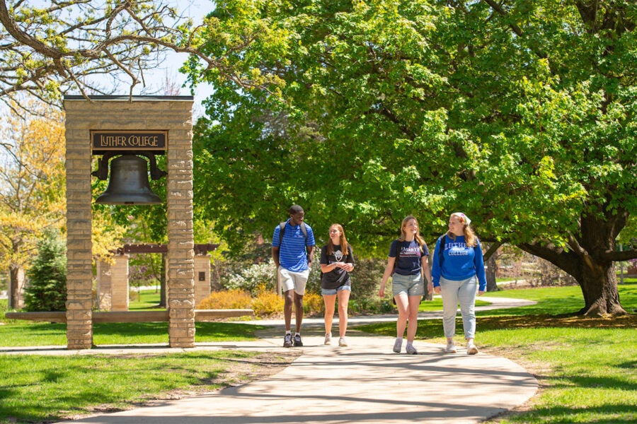 Four college students walk to class on campus
