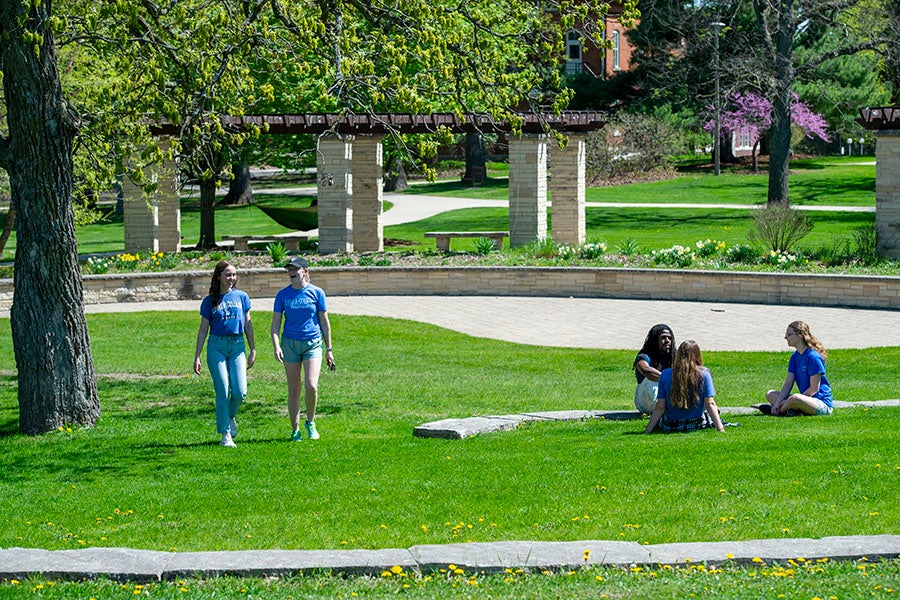 Students sitting and walking on the green space in the middle of campus