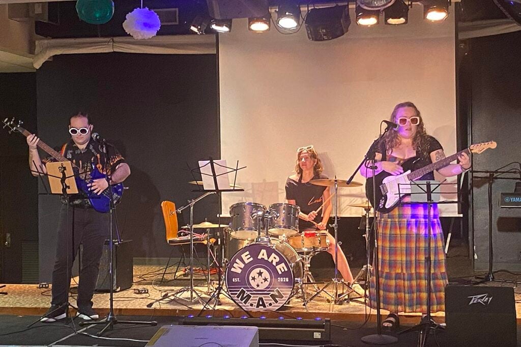 A 3-piece rock band performing on stage.
