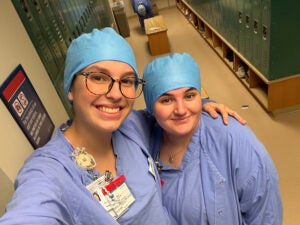 Two students in nursing scrubs taking a selfie in a hospital locker room.