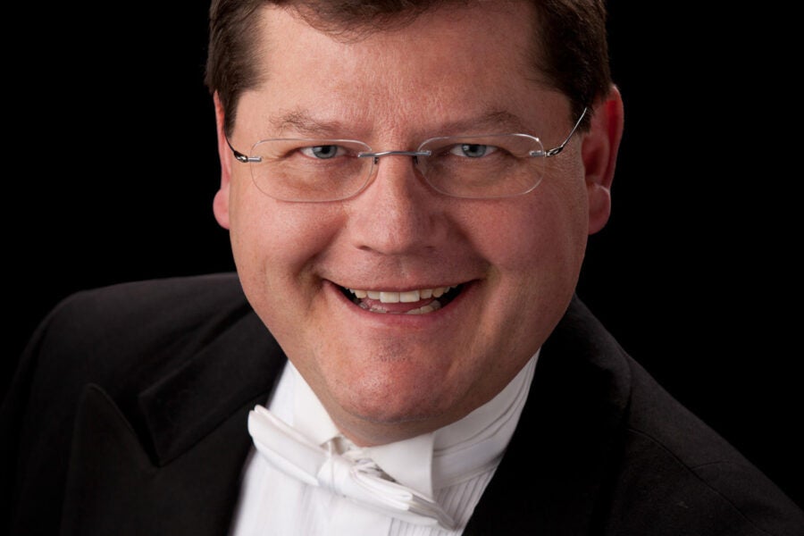 professional headshot of a choral conductor wearing a white bow tie, white shirt and black jacket