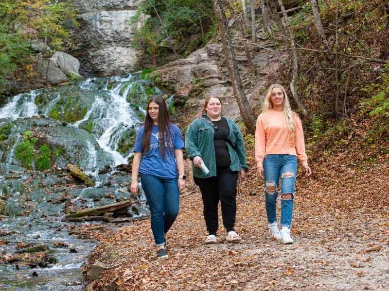 Three students walk away from a waterfall