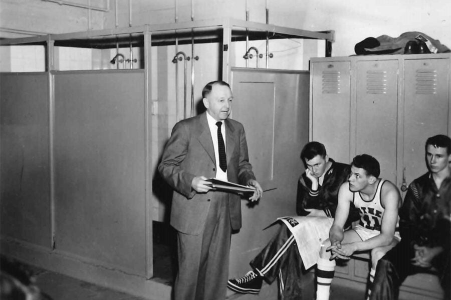 Hamlet Peterson talking to basketball players in a locker room.