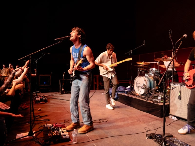 A band on stage, with a singer and guitar player at the center.