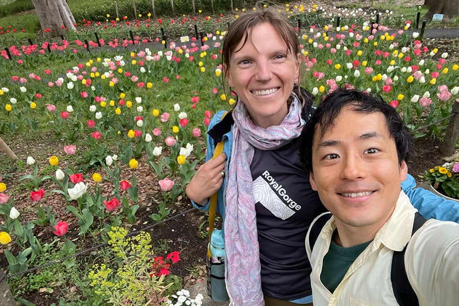 Two people take a selfie in front of a field of tulips