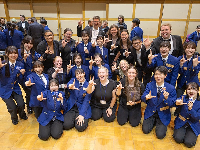 Luther students and Japanese students pose for a photo holding up their hand to make the L sign