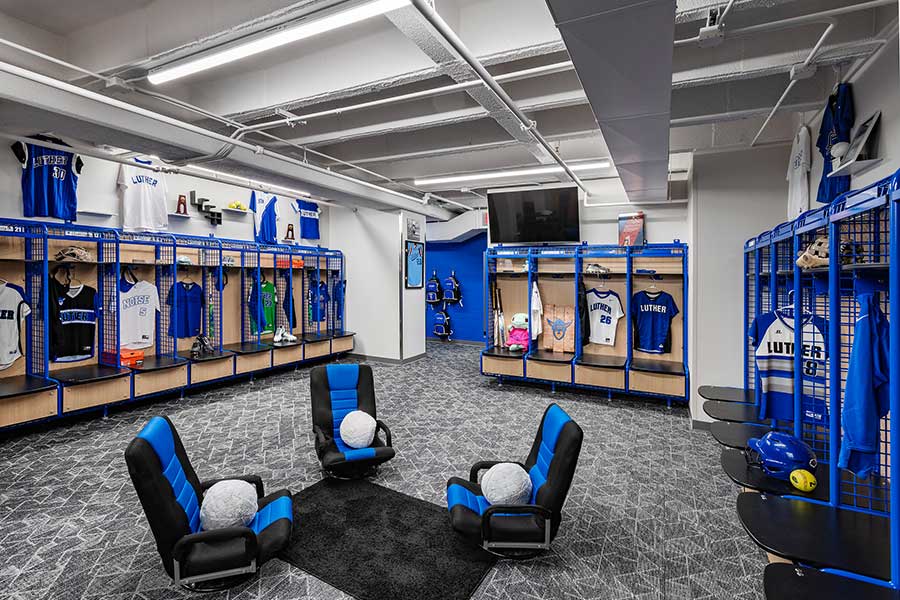A view of a carpeted locker room with three chairs in the middle