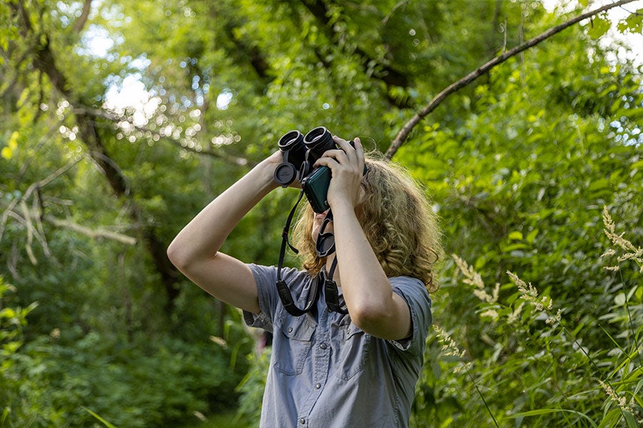 A young man with binoculars held up to his eyes