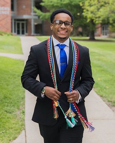 A young man in a suit wearing lots of colored cords