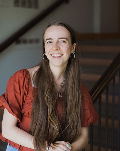 A smiling woman in rust-colored shirt